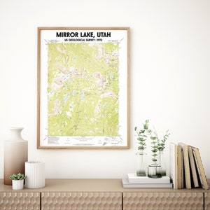 May include: A framed topographic map of Mirror Lake, Utah, from the US Geological Survey, 1972. The map features green and tan terrain with blue lakes and is displayed in a light brown wooden frame. The text "MIRROR LAKE, UTAH" is at the top.