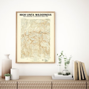 May include: A framed vintage map print of the High Uinta Wilderness, Uinta Mountains, from the US Geological Survey 1905. The map features a detailed topographic view in shades of brown and beige, encased in a light wood frame.
