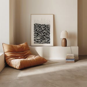 Op de afbeelding: Een zwart-witte abstracte print van een landschap met een reeks golvende lijnen. De print is ingelijst in een eenvoudige houten lijst en hangt aan een witte muur.