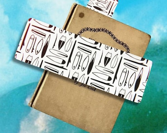 May include: A stack of vintage books with white and black surfboard pattern bookmarks. The bookmarks are rectangular and feature various surfboard designs. The books have a tan cover and are set against a blue and green background.