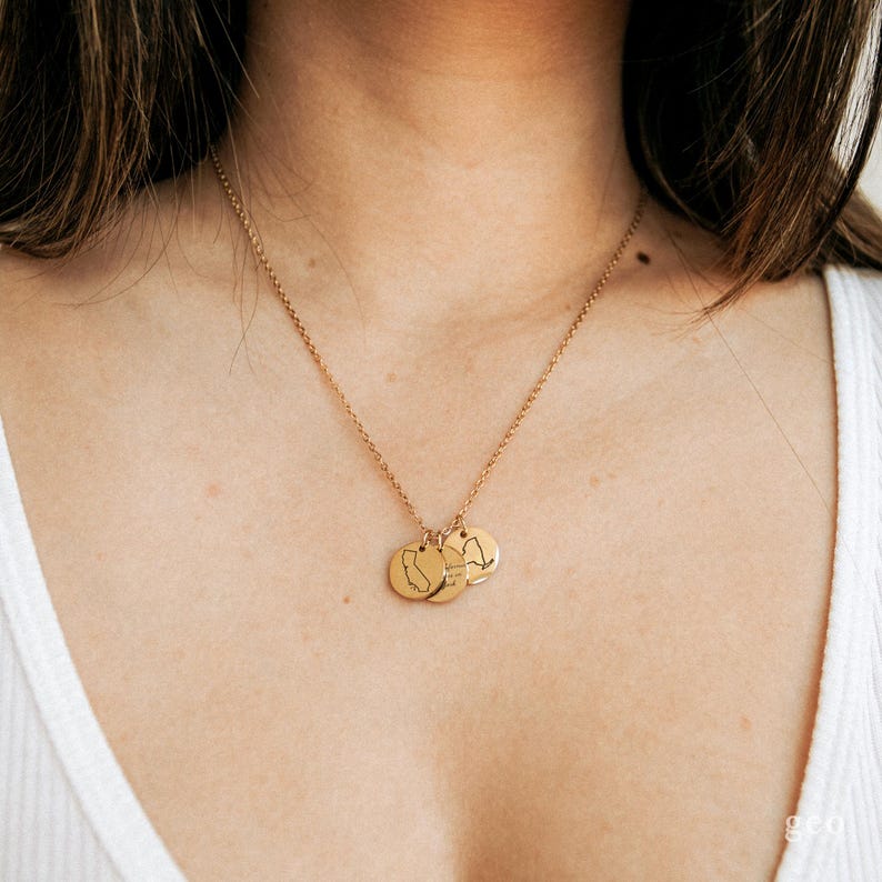 May include: A gold necklace with three small round pendants. Each pendant features a different state outline.
