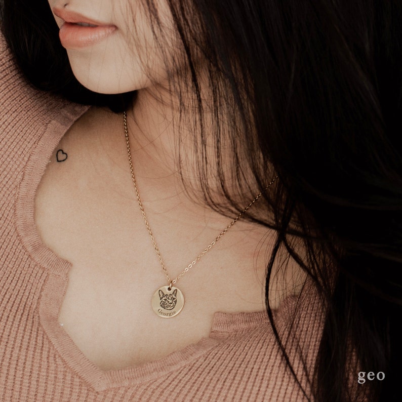May include: A gold chain necklace with a round pendant featuring a dog's face and the name "George" engraved on it.