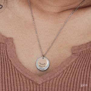 May include: A silver chain necklace with a layered pendant featuring three circular discs. The discs are engraved with the names "Jackson", "Marcus", and "Cindy".