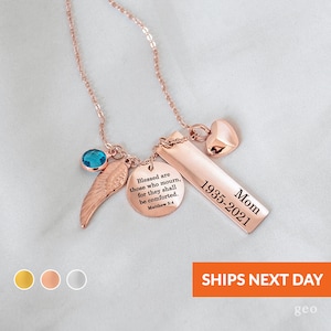 May include: Rose gold necklace with a heart charm, a small blue gemstone, a wing charm, and a bar charm with the text "Blessed are those who mourn, for they shall be comforted. Matthew 5:4" and "Mom 1935-2021".