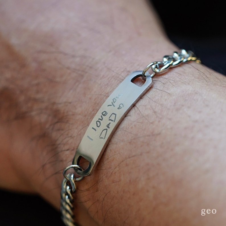 Puede incluir: Un brazalete de cadena de plata con una etiqueta rectangular que dice "Te amo pap&aacute;".