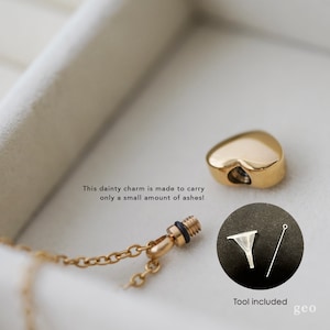 May include: Gold heart-shaped cremation charm necklace with a small funnel and a tool for filling the charm with ashes. "This dainty charm is made to carry only a small amount of ashes!" and "Tool included geo" are written on the image.