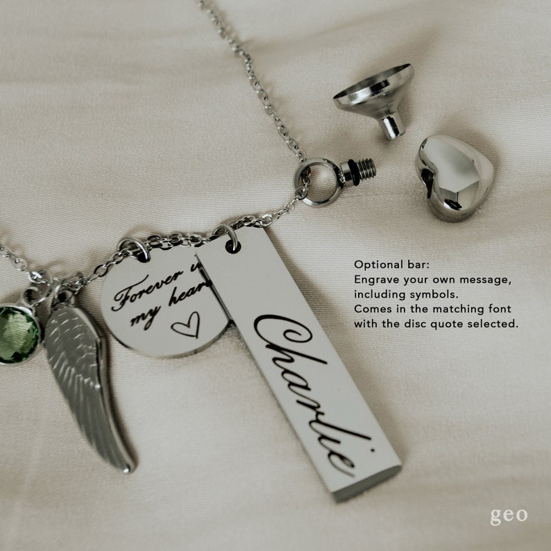 May include: Silver necklace with a small heart charm, a round charm with the inscription "Forever in my heart", a small green gem, a silver wing charm, and a rectangular bar charm with the inscription "Charlie".