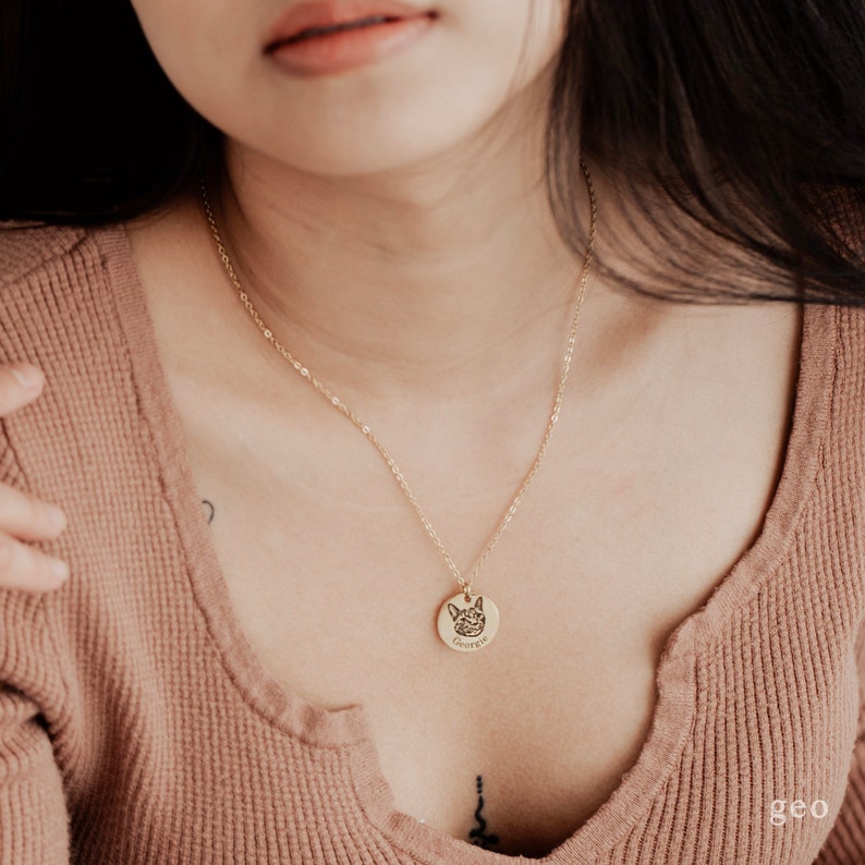 May include: A gold chain necklace with a round pendant featuring a dog's face and the name "George" engraved on it.