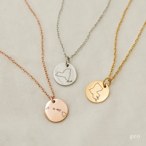 May include: Three necklaces with different state outlines on circular pendants. The necklaces are silver, gold, and rose gold. The states are New York, Maine, and Hawaii.