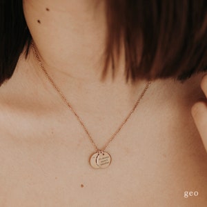 May include: A rose gold necklace with two round pendants. The larger pendant has the text "It's always beach weather" engraved on it.