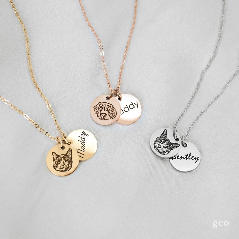 Op de afbeelding: Drie gouden kettingen met gepersonaliseerde huisdierportretten en namen. De kettingen bevatten een hondenportret met de naam "Buddy", een kattenportret met de naam "Maddy" en een kattenportret met de naam "Bentley".