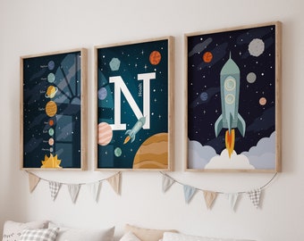 Pode incluir: Três impressões emolduradas com tema espacial. As impressões apresentam um foguete, planetas e a letra N com o nome Noah. As impressões estão penduradas em uma parede branca acima de um banco de madeira com recipientes de armazenamento.