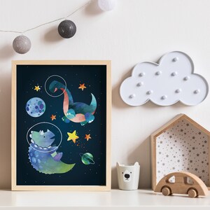 May include: A framed print depicting two blue and green dinosaurs in space. The dinosaurs are wearing astronaut helmets and are surrounded by stars, planets, and a moon.