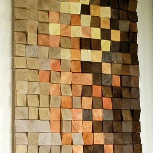 Peut inclure: Une œuvre d'art murale composée de blocs de bois dans différentes nuances de brun, beige et orange. Les blocs sont disposés en quinconce, créant un effet texturé et dimensionnel.