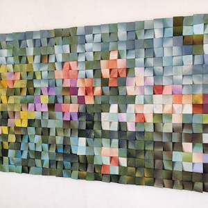 Può includere: Un'opera d'arte murale realizzata con blocchi di legno, disposti a mosaico. I blocchi sono dipinti in tonalità di blu, verde, giallo, rosa e viola, creando un design colorato e astratto.