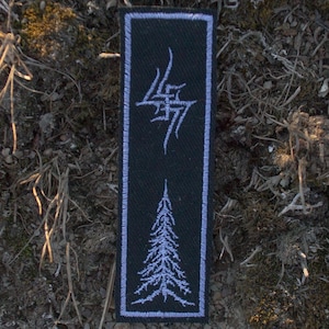 May include: A rectangular black patch with a white border. The patch features a stylized lightning bolt design at the top and a detailed white tree at the bottom. The patch is set against a backdrop of dirt and moss.