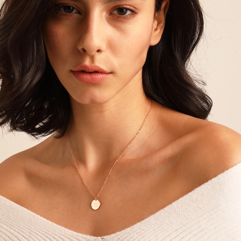 May include: A gold necklace with a small round pendant. The pendant is smooth and has a subtle shine.