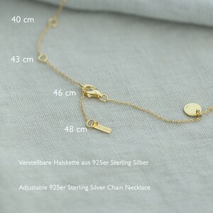 May include: A gold chain necklace with a small round charm. The necklace is adjustable and measures 40, 43, 46, and 48 cm. The necklace is made of 925 sterling silver.