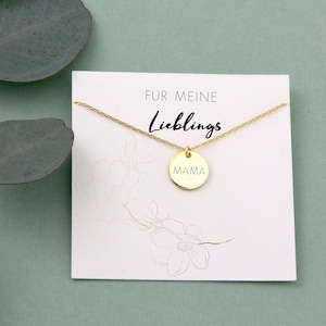 May include: Gold necklace with a round pendant that says "MAMA" on it. The necklace is on a white card with the text "F&uuml;r meine Lieblings" on it.