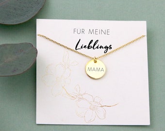 May include: Gold necklace with a round pendant that says "MAMA" on it. The necklace is on a white card with the text "Für meine Lieblings" on it.