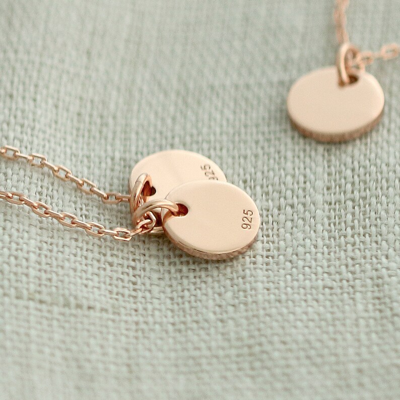 May include: A rose gold necklace with two round pendants. The pendants are engraved with the number "925".