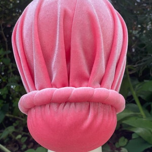 May include: A pink velvet turban with a gathered top and a gathered band around the bottom.
