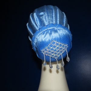 May include: A blue velvet bun maker with a crystal embellishment. The bun maker is designed to create a smooth, polished bun.