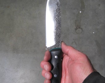May include: A silver knife with a black handle and a green accent. The knife has a textured blade and a black handle with three silver rivets.