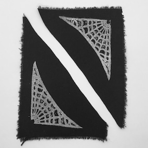 May include: Two black fabric patches with a white spiderweb design. The patches are cut in a triangular shape and have a frayed edge.