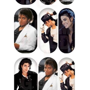 May include: A collection of oval-shaped nail art decals featuring images of Michael Jackson in various poses. The decals showcase the singer in black jackets, white suits, and hats. The Gold n' Glam Beauty logo is at the top.