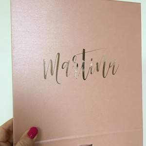 May include: A blush pink box with a gold foil inscription that reads "Martina".