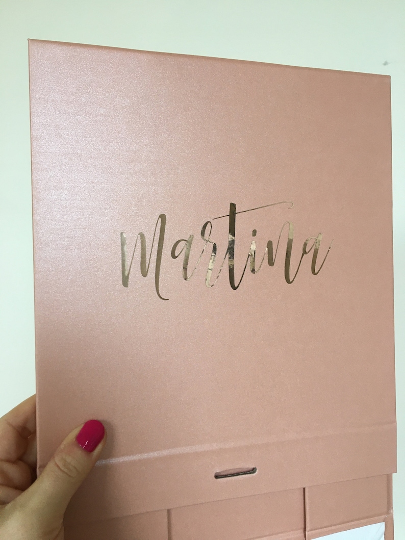 May include: A blush pink box with a gold foil inscription that reads "Martina".