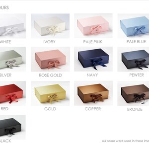 May include: A collection of thirteen rectangular gift boxes with hinged lids and ribbon closures, displayed in various colors including white, ivory, pink, blue, silver, rose gold, navy, pewter, red, gold, copper, bronze, and black.
