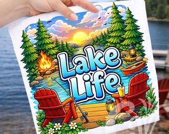 May include: A white square towel with a colorful illustration of a lake scene. The image features a sunset, trees, a campfire, Adirondack chairs, and the words "Lake Life" in blue and white. A fishing rod is also visible.