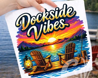 May include: White graphic tee featuring a lakeside scene with Adirondack chairs on a dock, a fishing pole, and a sunset. The text "Dockside Vibes" is in a stylized font above the scene. A lantern is on the dock.