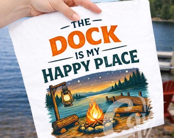 May include: White square towel with the text "THE DOCK IS MY HAPPY PLACE" in orange and white. The design features a campfire, dock, lake, and lantern. The towel is held by a person.