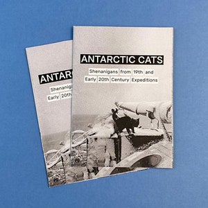 Könnte beinhalten: Ein Schwarzweißfoto einer Katze in einer schneebedeckten Landschaft. Der Text auf dem Cover lautet "ANTARCTIC CATS Shenanigans from 19th and Early 20th Century Expeditions".