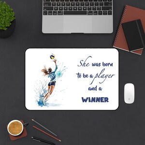 May include: White rectangular mousepad featuring a watercolor illustration of a volleyball player in action, with blue and white accents. Text reads "She was born to be a player and a WINNER."
