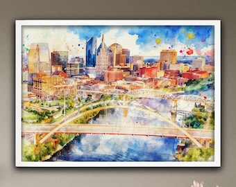 May include: Watercolor painting of the Nashville, Tennessee skyline, framed in white. The artwork depicts the city's buildings, bridges, and river in shades of orange, yellow, and blue, with colorful paint splatters in the sky.