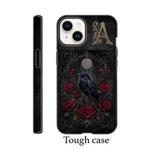 May include: A black phone case featuring a dark, intricate design with a central black raven perched amidst deep red roses and ornate filigree patterns. The letter A is displayed in the upper right corner, and a circular moon motif sits above the bird.