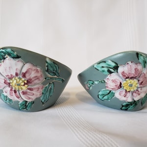 Peut inclure: Deux bols en céramique de couleur gris-vert, chacun orné d'un grand motif floral détaillé. Les fleurs présentent des pétales roses, des centres jaunes et des feuilles vertes, créant un accent décoratif.