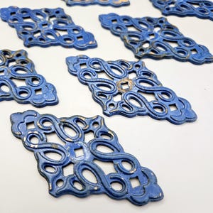 Peut inclure: Plusieurs pièces décoratives en métal bleu avec un design ajouré orné. Les pièces ont une finition vieillie avec des accents dorés et sont en forme de losange avec un centre carré. Elles sont probablement destinées à des meubles ou à des projets d'artisanat.