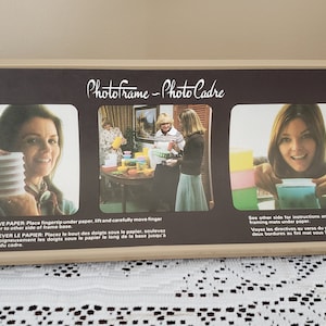 Peut inclure: Un cadre photo vintage avec un fond marron et un cadre beige. Le cadre contient trois photos de femmes. Le texte "Photoframe - Photo Cadre" et des instructions en anglais et en français sont présents.