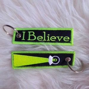 I BELIEVE Stickschlüsselanhänger mit einem süßen Ufo mit Alien auf der Rückseite
