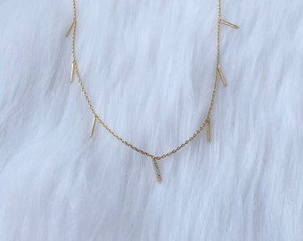 Delicate gold bar necklace with dainty golden charms