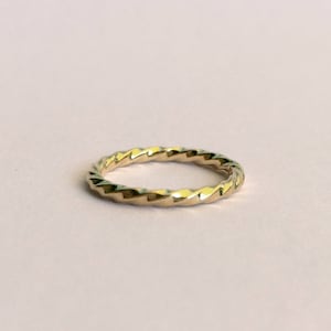 Puede incluir: Un anillo de banda de oro con un diseño retorcido y texturizado.