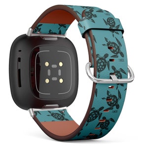 Può includere: Uno smartwatch nero con un cinturino in pelle turchese e marrone con un motivo ripetitivo di tartarughe marine nere. Il cinturino ha la scritta "TURTLE" stampata.