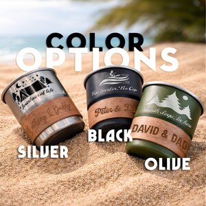 K&ouml;nnte beinhalten: Drei Reisebecher in Silber, Schwarz und Olivgr&uuml;n, jeweils mit einem einzigartigen Design und Lederband. Der silberne Becher zeigt eine Campingszene, der schwarze Becher einen Surfer und der olivfarbene Becher eine Berglandschaft. Der Text "COLOR OPTIONS" steht oben.