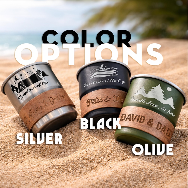 K&ouml;nnte beinhalten: Drei Reisebecher in Silber, Schwarz und Olivgr&uuml;n, jeweils mit einem einzigartigen Design und Lederband. Der silberne Becher zeigt eine Campingszene, der schwarze Becher einen Surfer und der olivfarbene Becher eine Berglandschaft. Der Text "COLOR OPTIONS" steht oben.