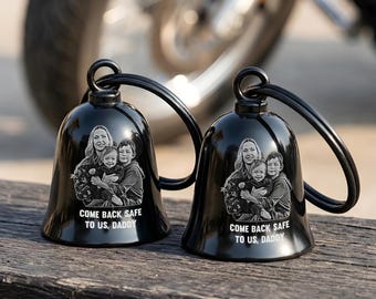 May include: Two black metal bells with attached key rings, each featuring a laser-engraved photograph of a woman and two children. Below the image, the text reads, "COME BACK SAFE TO US, DADDY" in white capital letters on the glossy bell surface.